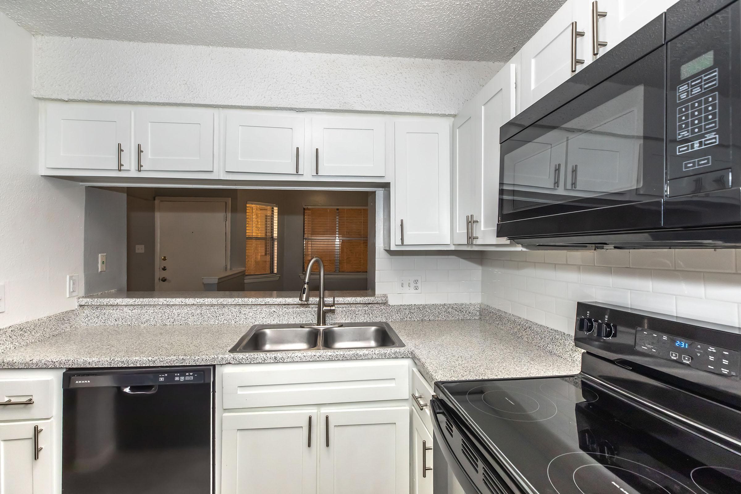 Cocina renovada con cubierta tipo granito y gabinetes blancos en Providence at Domain